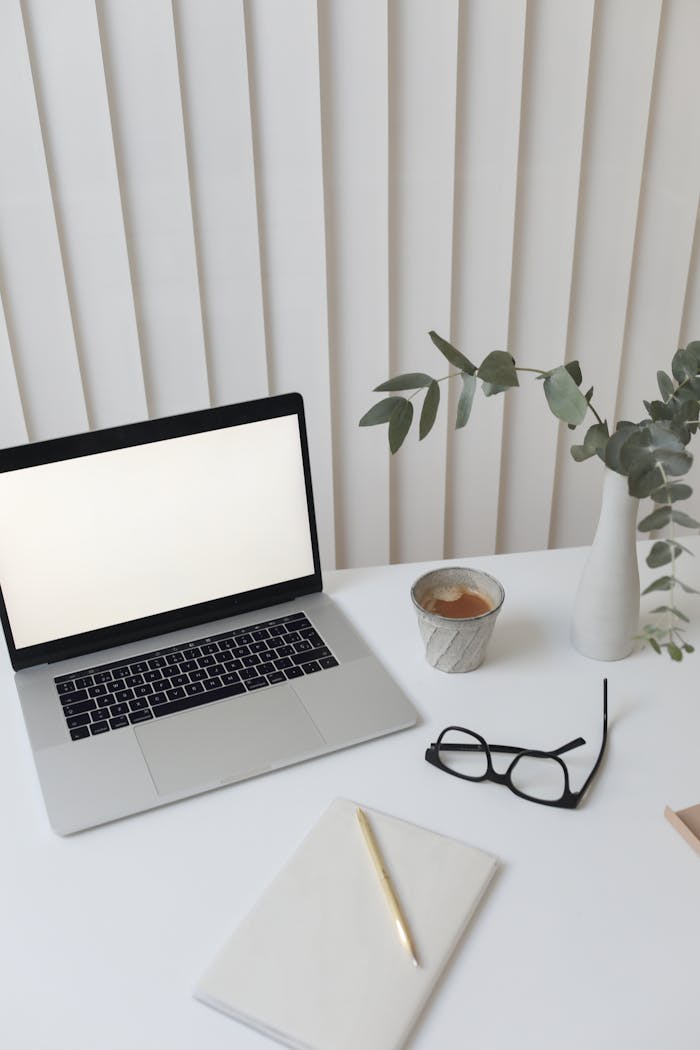 Elegant workspace featuring a blank-screen laptop, coffee, and decor for a modern office setting.